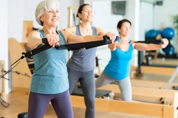 Toning Arms After 60: Empowering Womens Fitness Through Effective Weight Training 2 older woman doing weight training Rugby and resistance in the gym to tone upper arms